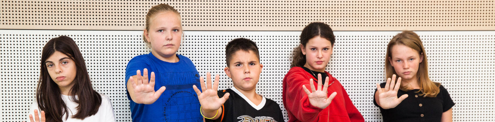 Fünf Kinder signalisieren mit ihrer ausgestreckten Hand „Stopp!“ 