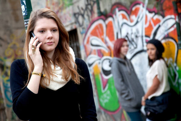 Mädchen telefoniert draußen mit ihrem Smartphone.